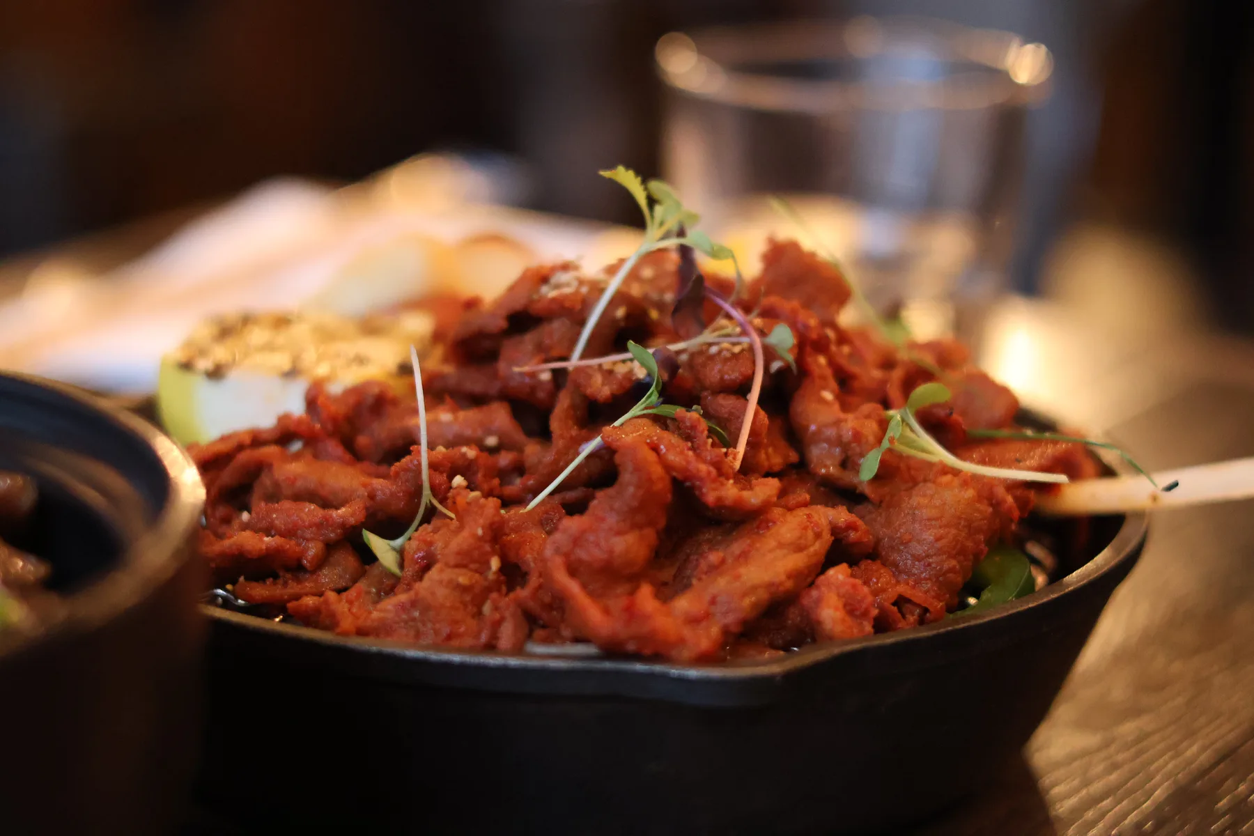Crispy reddish-brown meat garnished with microgreens