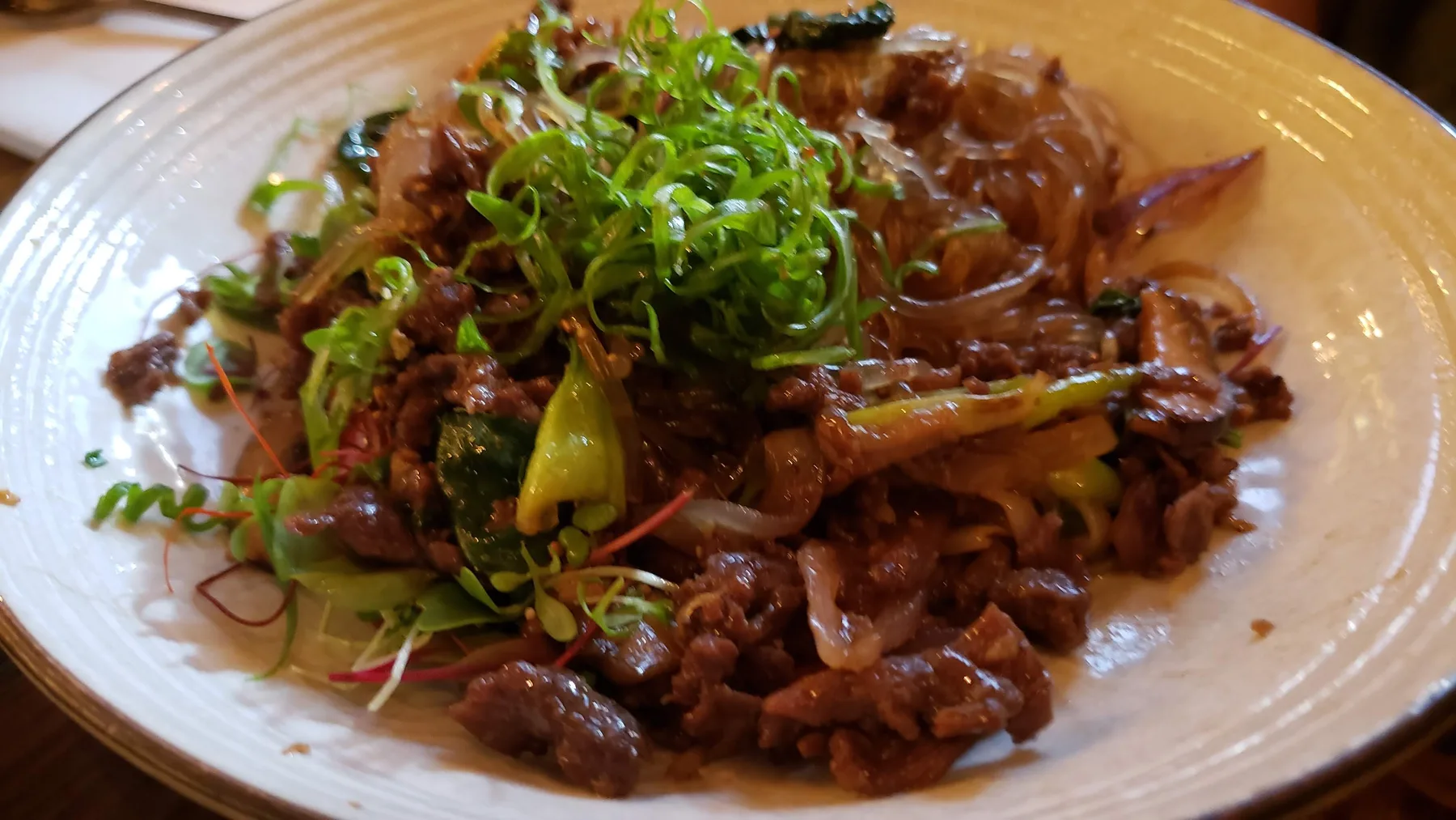 Stir-fried meat and vegetables topped with fresh sprouts
